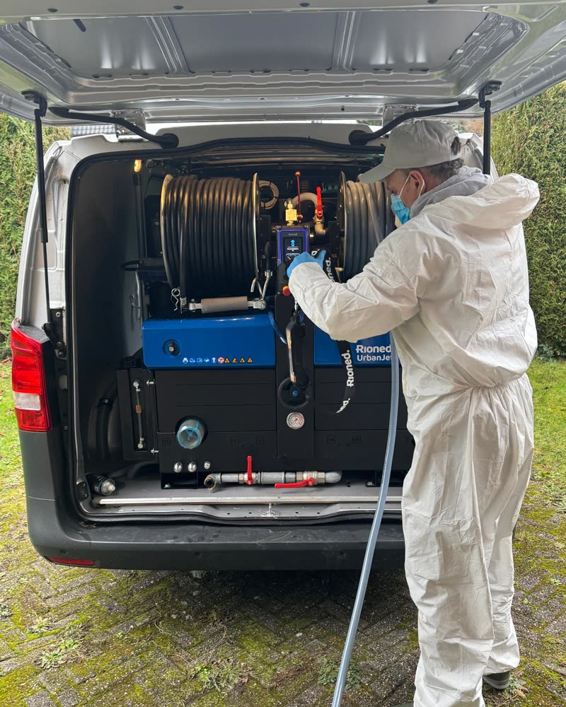 Technician in protective gear at the high-pressure machine in the back of the van.