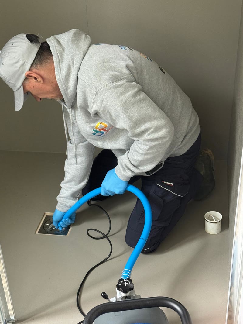 Technician feeding the electric drain rod into a shower drain.