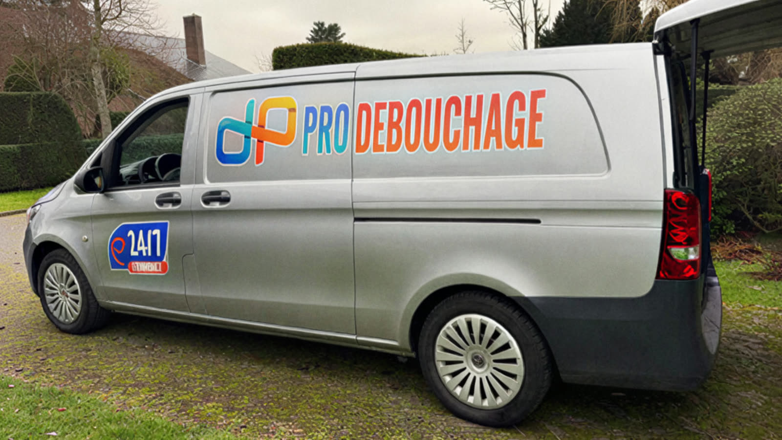 The van in a garden, the Pro Débouchage logo on the side.